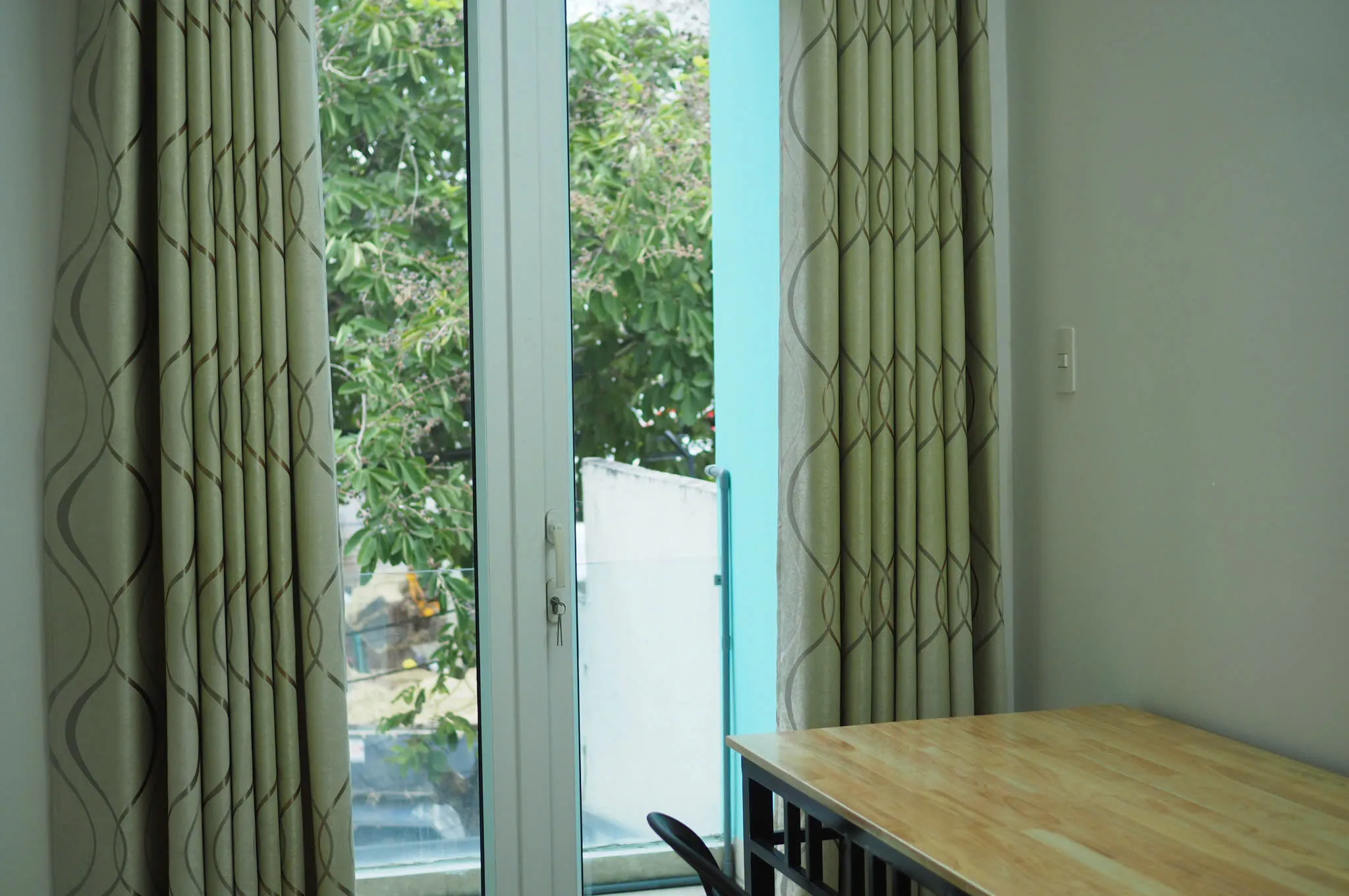 Glass balcony door, curtains and a wood table
