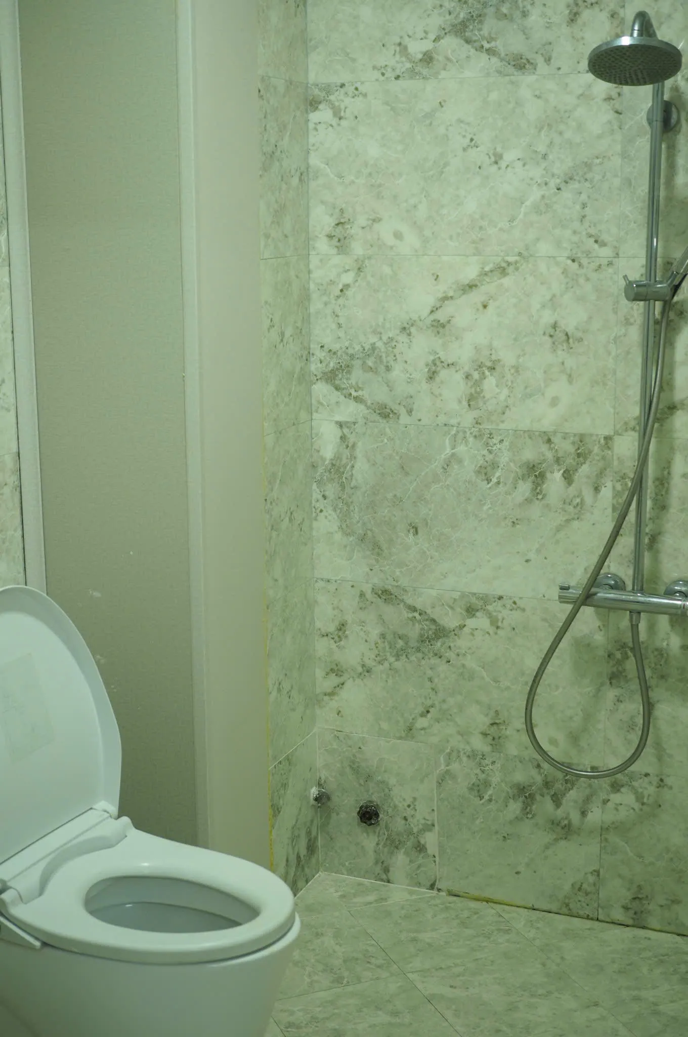 Studio bathroom with marble-look tiles, toilet and shower