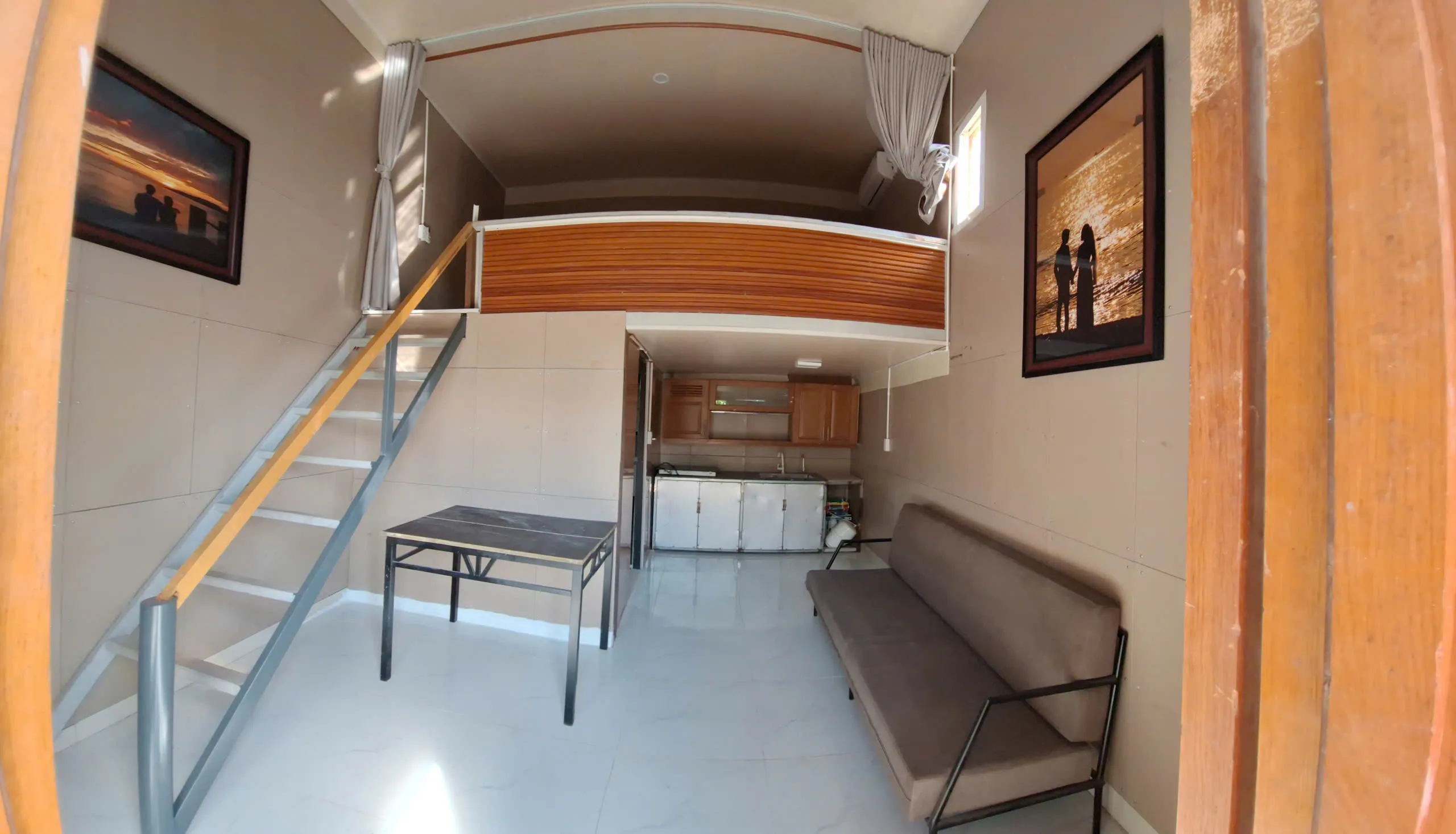 Loft living room with sofa, table and kitchen underneath