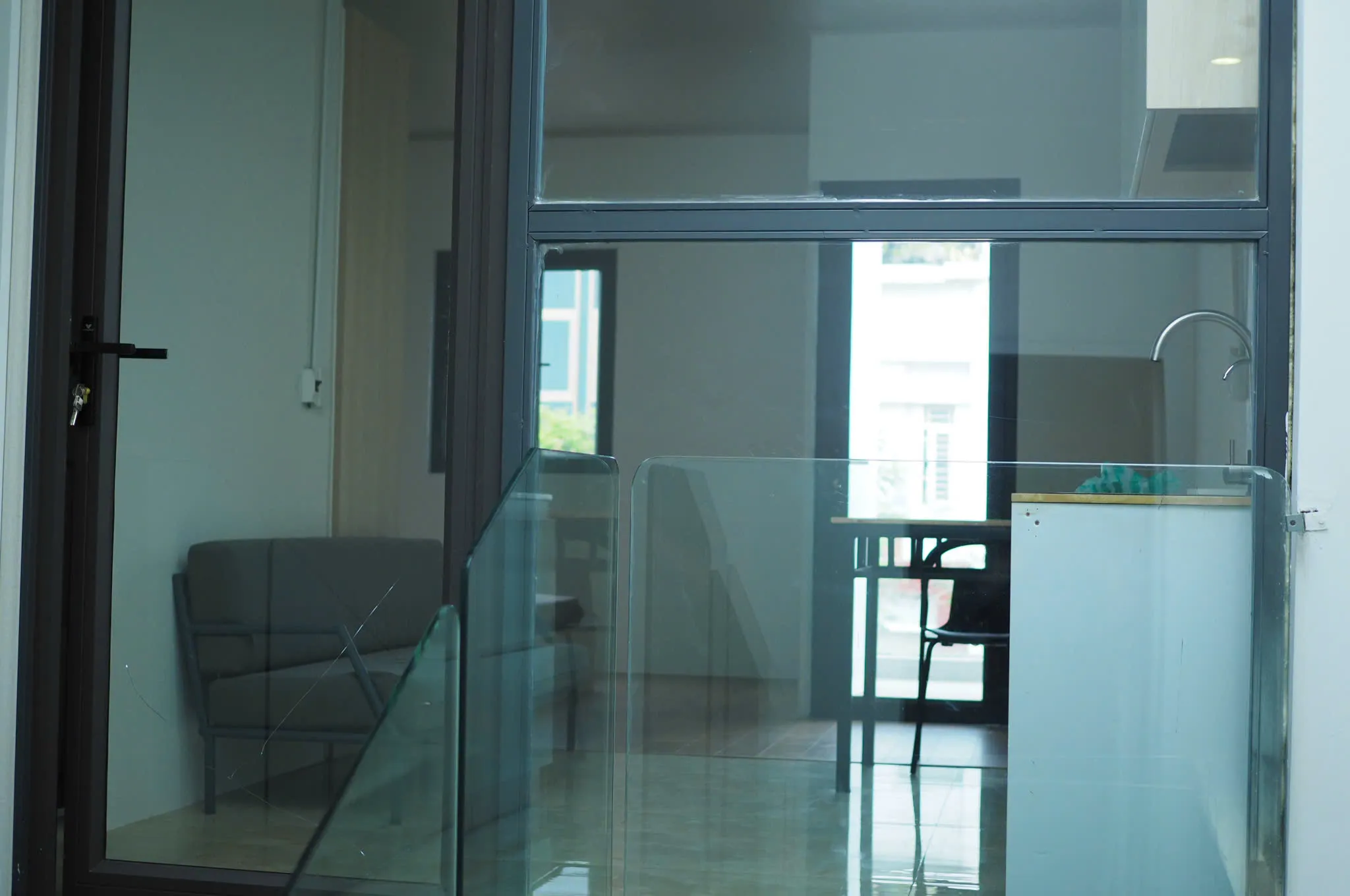 Glass entrance into the studio with sofa and dining table