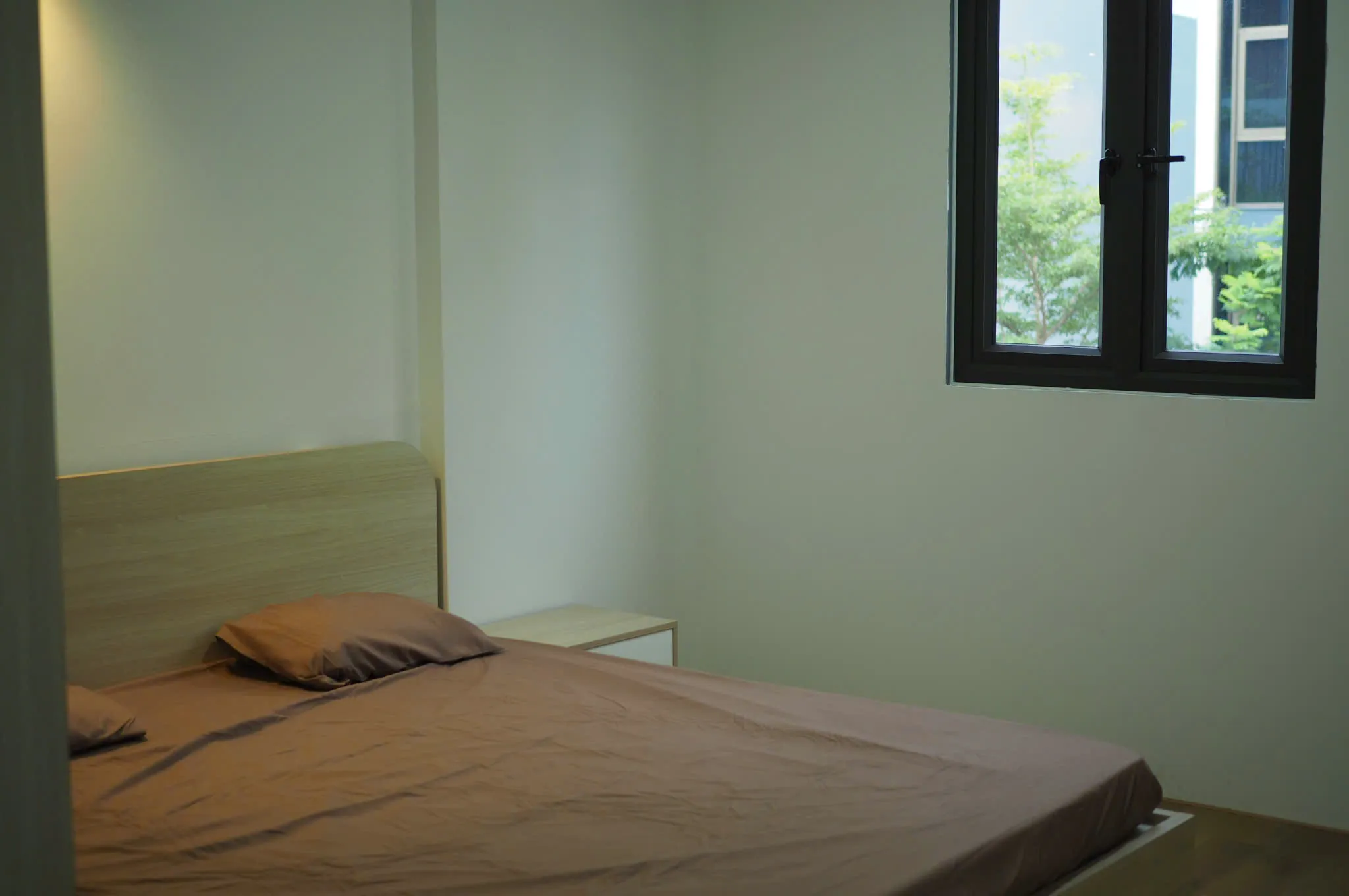 Studio bedroom with a bed and a window onto trees