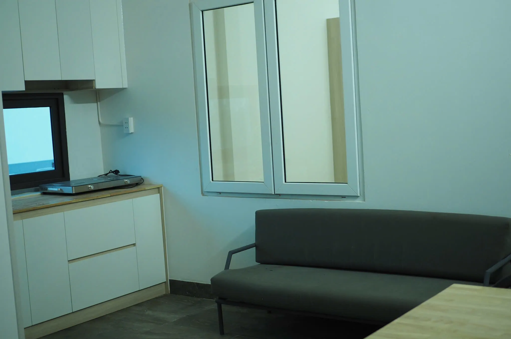 Grey sofa next to white kitchen cabinets